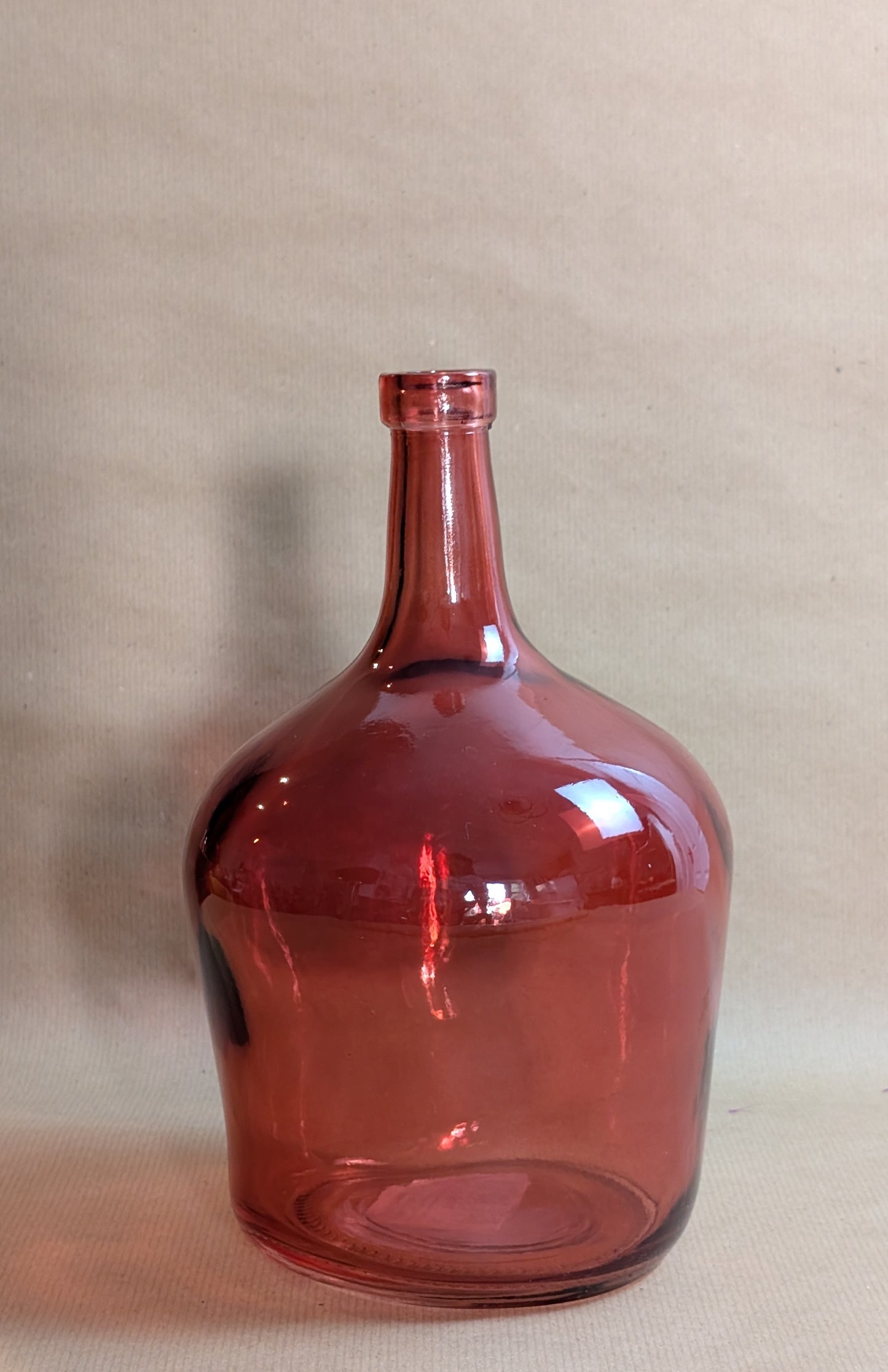 Red glass demijohn bottle on a beige background