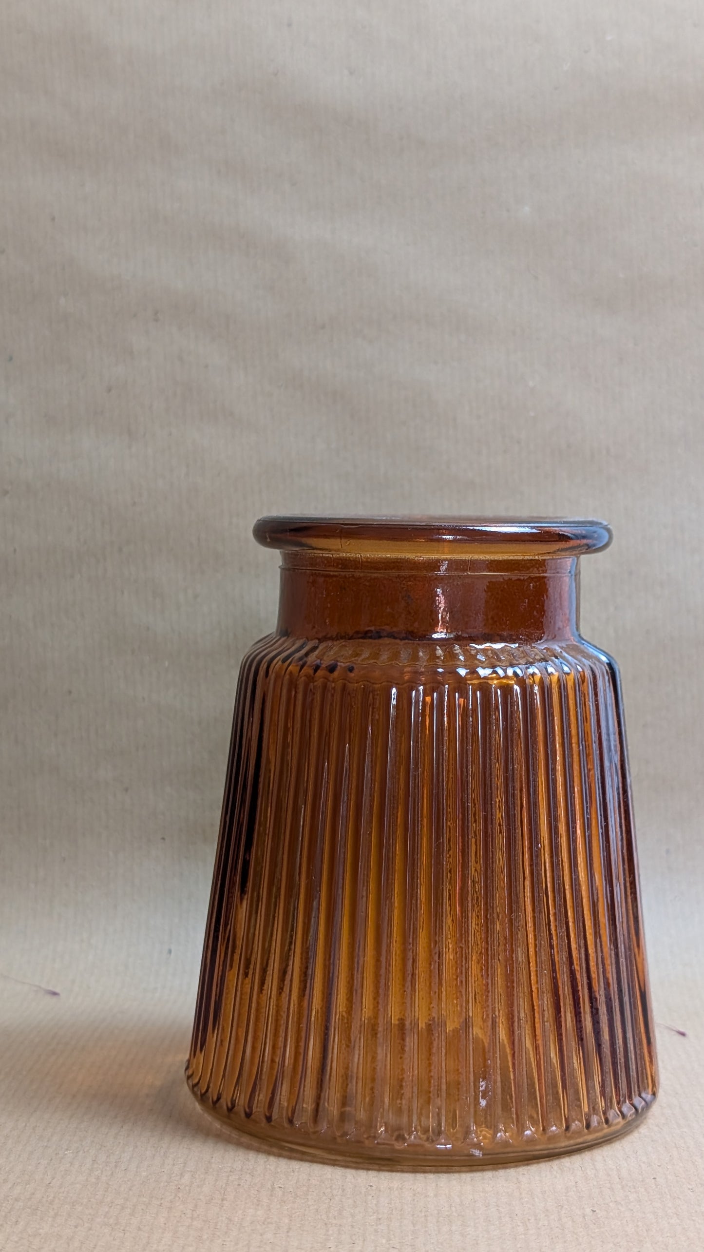 orange ribbed glass jar on a beige background