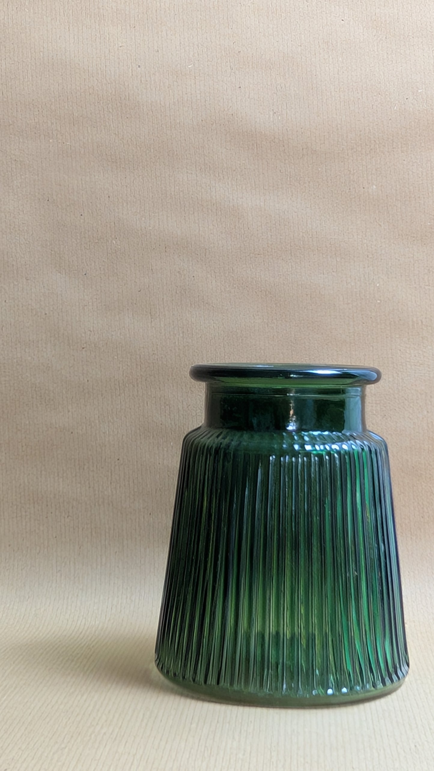 Green ribbed vase on a beige background