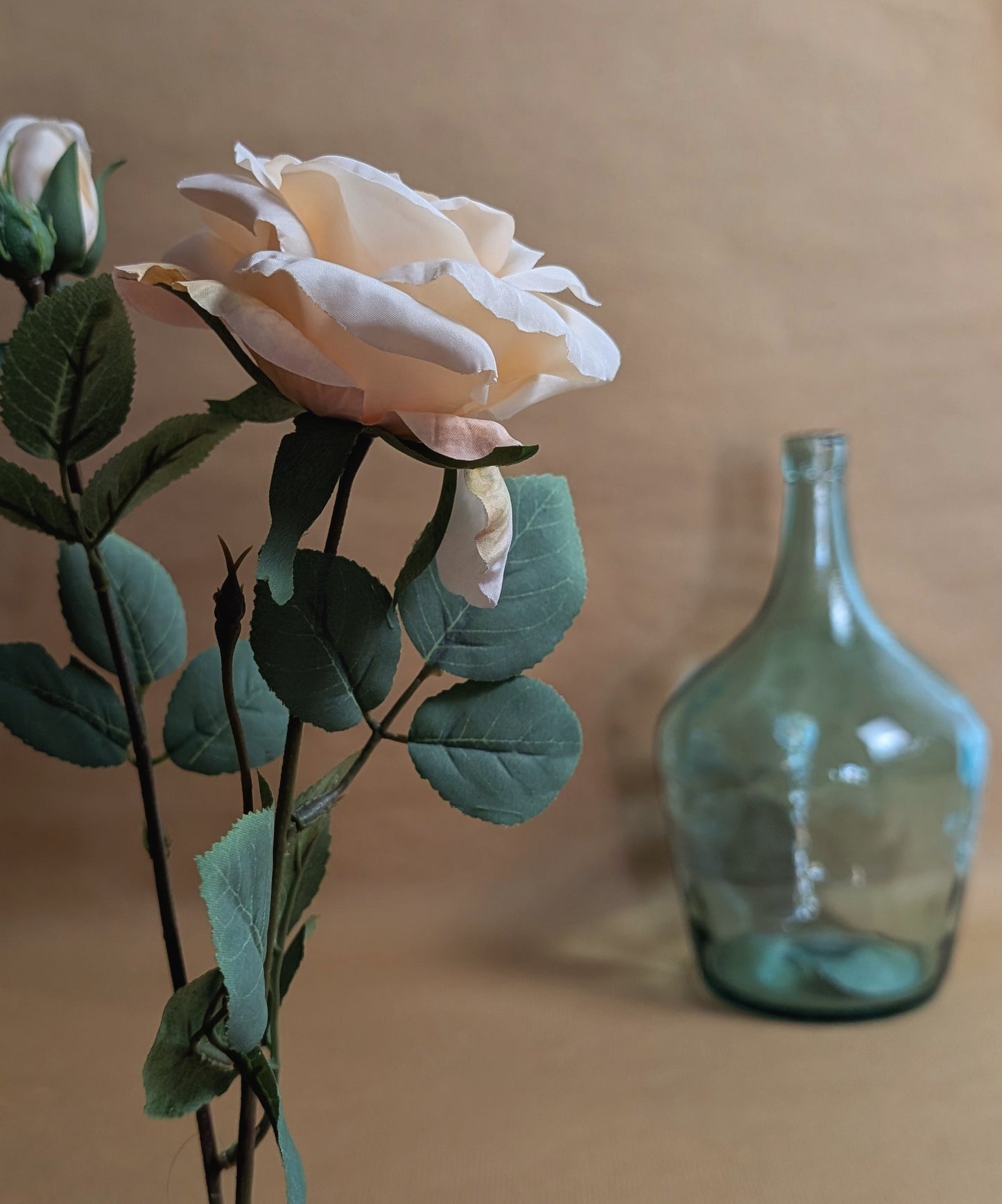 Bouquet of flowers with a green vase on a beige background