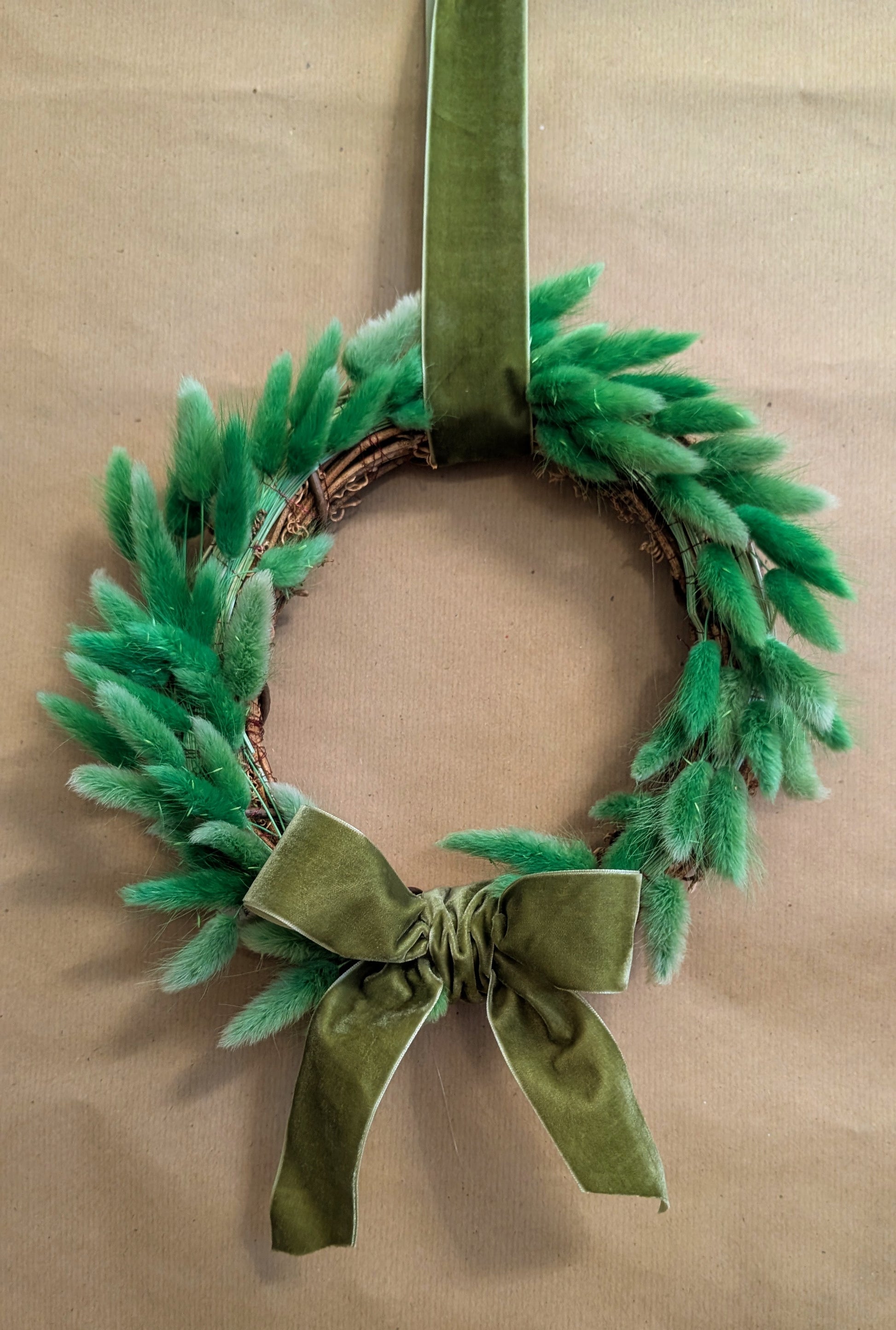 Green wreath with a bow on a beige background
