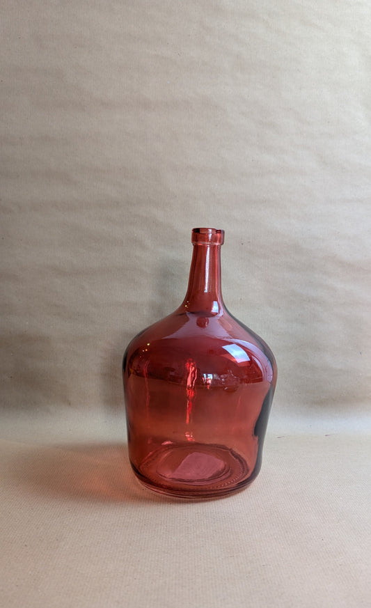 Red glass bottle on a beige background