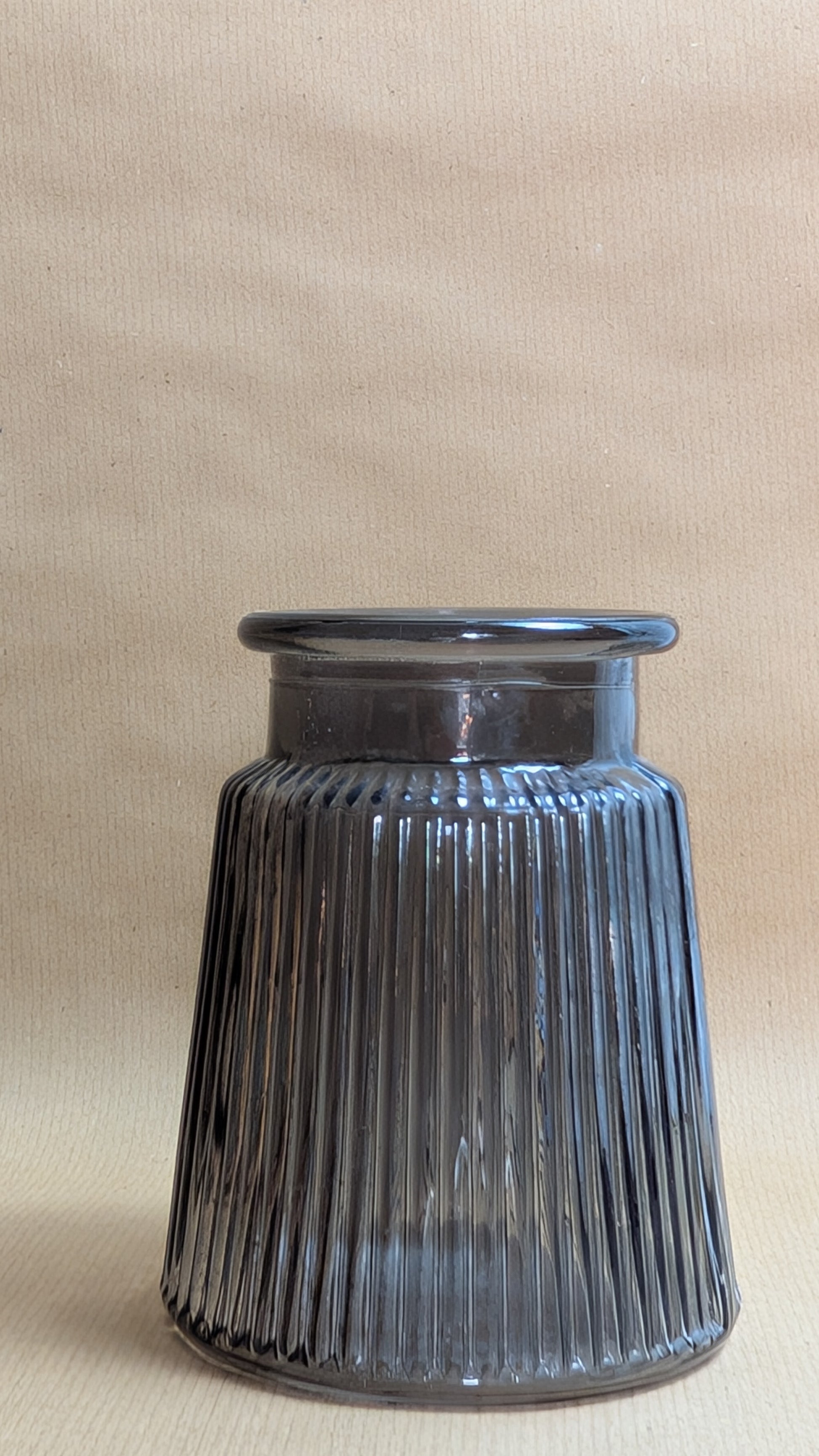 Grey ribbed glass vase on a beige background