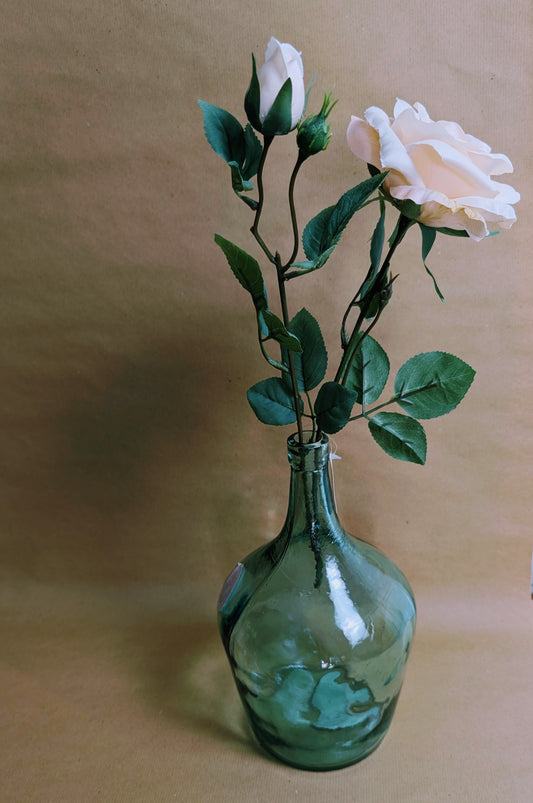 Green glass vase with white flowers on a beige background