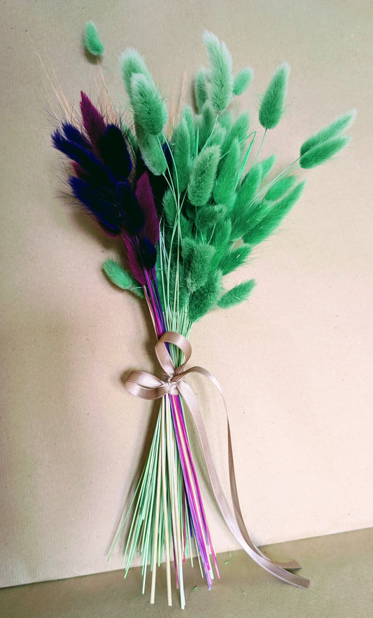 Bouquet of green and purple feathers tied with a ribbon on a light background