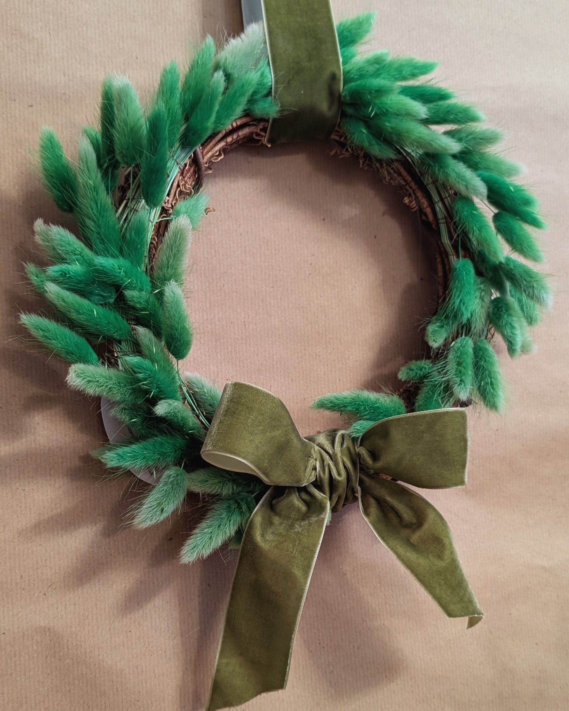 Green wreath with a bow on a beige background