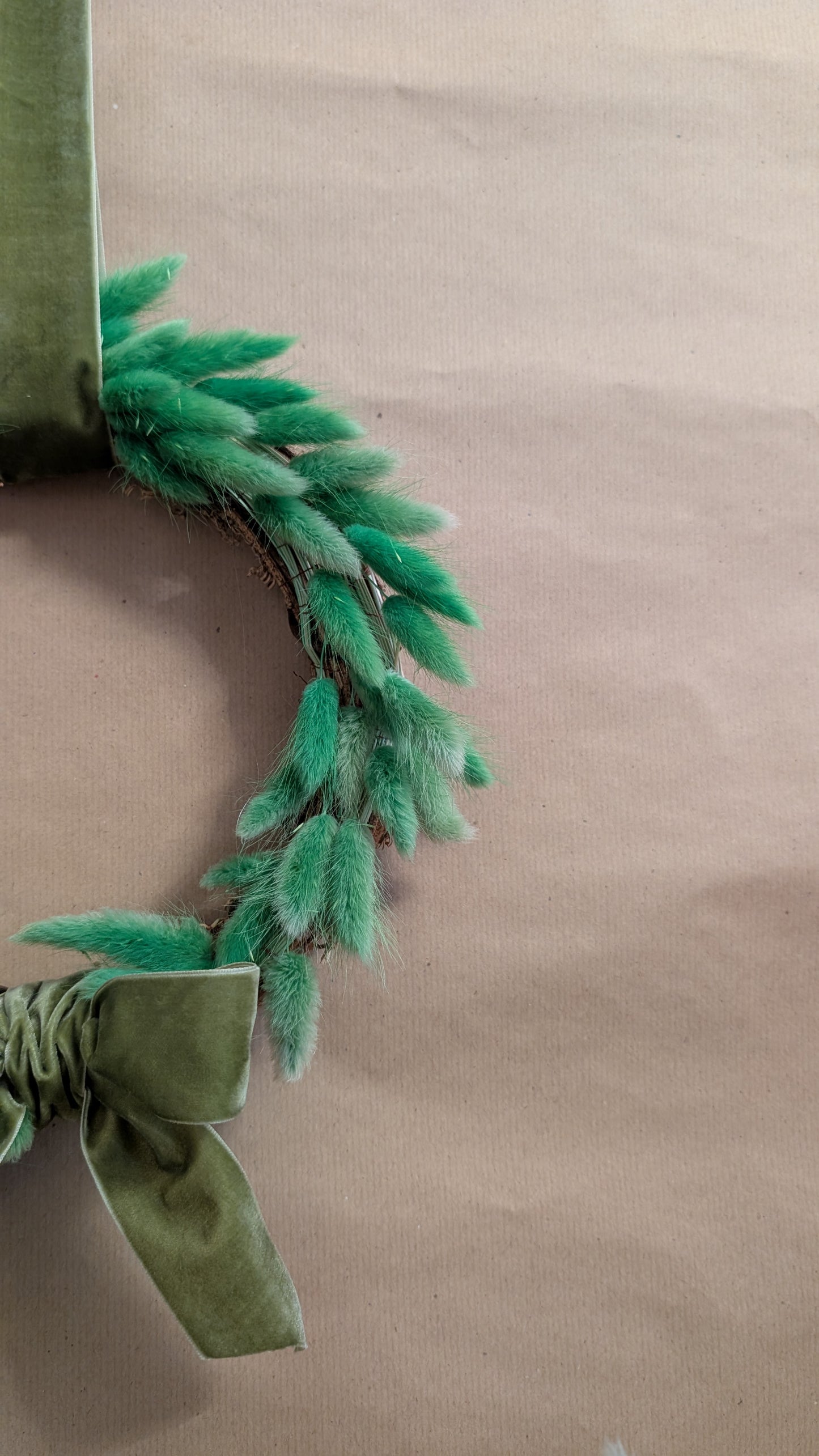 Green wreath with mustard velvet  bow on a beige background