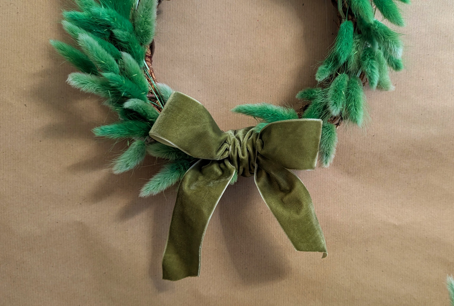 Green wreath with a bow on a beige background